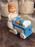 Front side view of vintage Marx Marty's Market toy showing the figure pushing a blue cart with fake food blocks.
