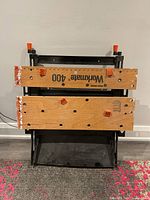 View of the wooden worktop panels from above, showing Black & Decker Workmate 400 labeling and orange clamps with some paint marks on edges.