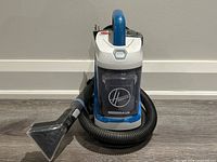 Front view of Hoover Power Dash wet vacuum with hose and nozzle attached.