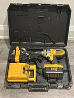 Photo of the DeWalt 36V cordless drill kit including drill, charger, additional battery, all inside a black hard plastic carrying case.