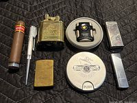 All seven lighters arranged on black fabric, showing variety and condition.