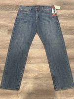 Full front view of the medium blue wash jeans laid flat, showing overall condition and cut.