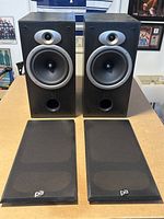 Pair of Precision Acoustics PA80 speakers from the front with grilles removed showing woofer, tweeter, and bass reflex port.