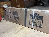 Cardboard box packaging displaying Vintage brand logo, maple leaf graphics, and 'Pioneered Solid Hardwood Flooring' text.