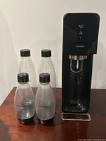 Full SodaStream unit standing with 4 accompanying plastic bottles in front, showing overall appearance and included bottles.