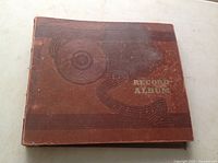 Brown vintage record album cover with musical note design and title 'Record Album' embossed, showing wear