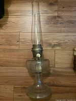Full view of the antique glass oil lantern showing the tall clear glass chimney and ribbed glass base.