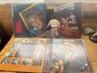 Front side of four vintage record albums showing cover art including Wilf Carter, Andy Gibb, and The Rookies.