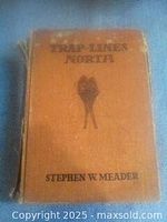 Photo of the front cover of the antique book titled 'Trap Lines of the North' showing author name Stephen W. Meader and bird illustration