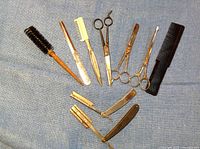 Top view of barber kit tools arranged on blue fabric including combs, scissors, brushes, and razors
