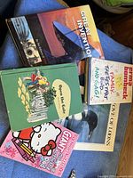 Top-down view of seven books stacked, showing various titles and covers.