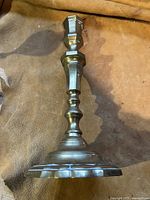 Side view of an old brass candlestick showing its ornate turned design and base.