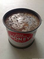 Angle showing the rusty metal top of the honey tin.
