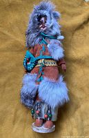 Full image of the doll standing on a circular base, showing the entire suede outfit with fur trim and bead decorations.