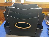 Front view of black plastic filing station showing multiple vertical compartments for files and side pockets for supplies.