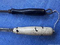 Two vintage forks with wooden handles, one black and one cracked white, placed on a blue surface.