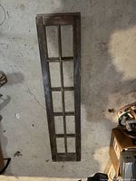 Top-down photo of dark stained antique wooden window frame with 8 glass panes on concrete floor