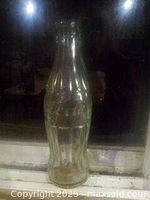 Front view of the green Coca-Cola bottle showing the embossed logo and contoured design.