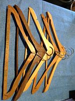 Five vintage wooden clothes hangers placed on blue fabric. Each hanger has a metal hook and wooden body with some vintage patina and markings.