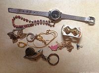 All items shown in one image: watch, bracelets, necklaces, pendants, novelty ring, keychain, and small jewelry pieces.