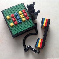 Photo of Lego phone toy showing green base with colorful Lego key buttons and black handset with colored blocks connected by coiled wire.
