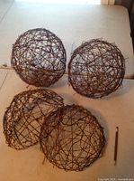 Three grapevine and wire balls placed on a table, showing general shape and appearance.