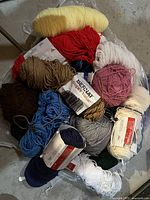 Top view of mixed color wool yarn skeins piled together, including yellow, red, white, pink, brown, blue.