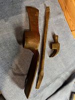 Three varied vintage metal tool heads and a metal rod on a fabric surface
