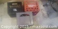 Photo showing three vintage plastic milk crates in black, gray, and orange colors placed on floor.