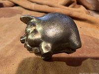 Side view of antique brass pig bank showing its full shape and texture.