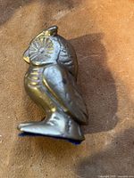 Side view of the solid brass owl figurine showing detailed feather texture and a round eye with a circular pattern.