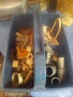 Blue plastic bin divided into compartments containing various plastic and PVC pipe fittings and connectors of different sizes and shapes.