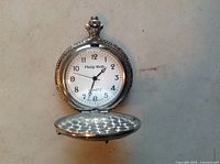 Front view of open pocket watch showing white face with black Arabic numerals and black hands. Philip Wells brand and Quartz labeled on dial.