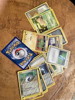 Photo showing assorted Pokémon cards scattered on a surface including multiple Aron cards, Trainer, and Energy cards visible