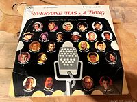 Front cover of the vinyl album titled Everyone Has a Song, showing multiple portraits of artists and a microphone graphic.