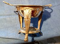 Side view of silver plate bowl on ornate stand showing detailed legs