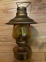 View of the full antique skating lantern with brass top, handle and yellow glass globe on wood background