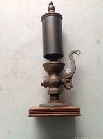 Full view of brass steam whistle showing lever, cylindrical top, and wood base