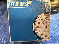 Blue box with Leonidas brand and stopwatch graphic, showing wear.