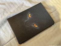 Front external view of the tablet case closed, showing the black cover with Black Panther eyes graphic.