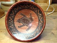 Top view of the terracotta bowl showing a painted frog design and geometric borders.