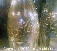 Close-up image showing embossed Coca-Cola logo on glass bottle indicating authenticity and vintage nature.