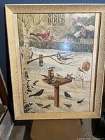 Full view of framed vintage poster showing birds and feeding station with snow and trees in background