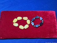 Yellow-toned amber bracelet and purple cats eye bracelet placed on red fabric background