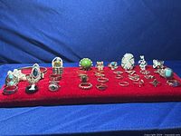 Photo showing 38 rings and 1 bangle bracelet on a red velvet display with blue background.