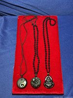 Three black onyx necklaces with pendants arranged on red velvet.