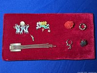 Photo showing 4 brooches and 4 rings arranged on red velvet background
