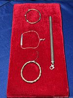 Top view of four sterling silver bracelets arranged on red velvet cloth, showing textured and mesh chain designs