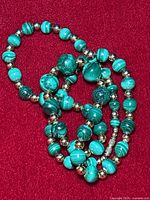 Close up of green malachite beads showing banded patterns and silver-tone spacer beads.