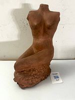 Front view of kneeling female nude sculpture showing torso and base
